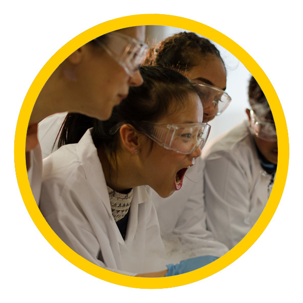 high school girl and friends watch exciting science experiment