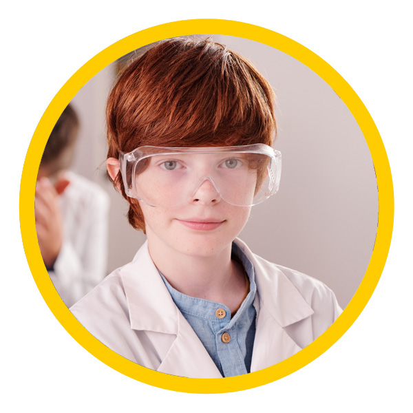 Middle school-aged student in safety goggles and lab coat